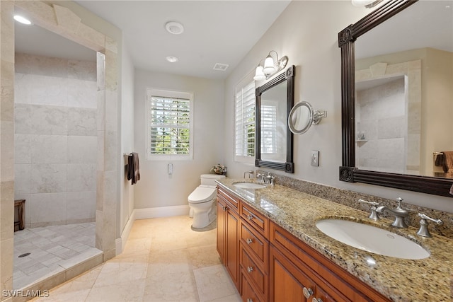 bathroom featuring a tile shower, vanity, and toilet