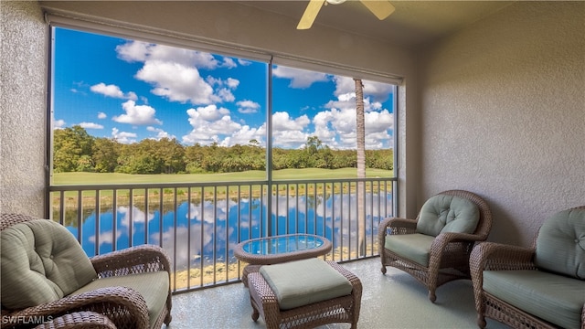 sunroom featuring ceiling fan and a water view