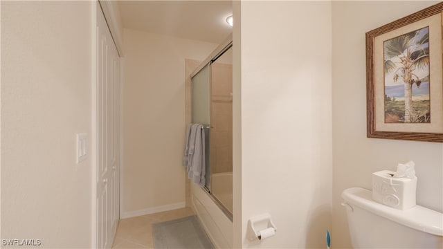 bathroom featuring combined bath / shower with glass door, tile patterned floors, and toilet