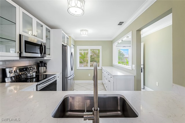 kitchen with white cabinets, stainless steel appliances, sink, and light stone countertops