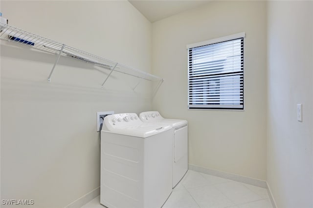 washroom featuring light tile patterned floors, washer and clothes dryer, laundry area, and baseboards