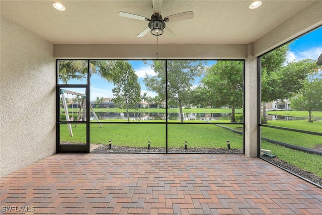 unfurnished sunroom featuring a water view and ceiling fan