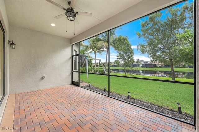 unfurnished sunroom with ceiling fan and a water view