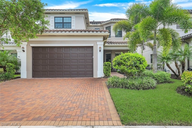 mediterranean / spanish home featuring a front lawn and a garage