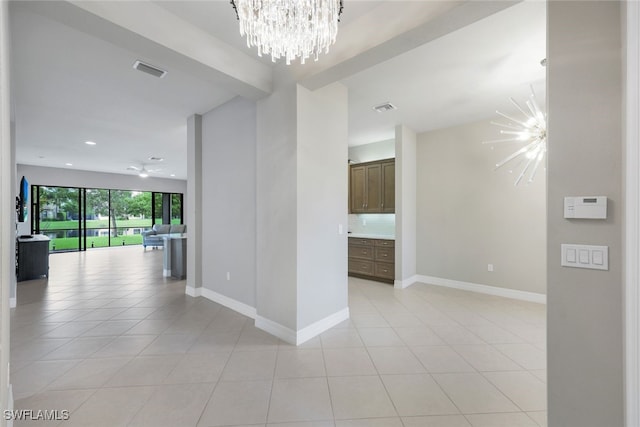 tiled empty room featuring a notable chandelier