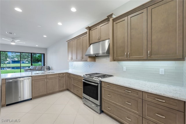 kitchen with ceiling fan, sink, backsplash, appliances with stainless steel finishes, and light stone countertops