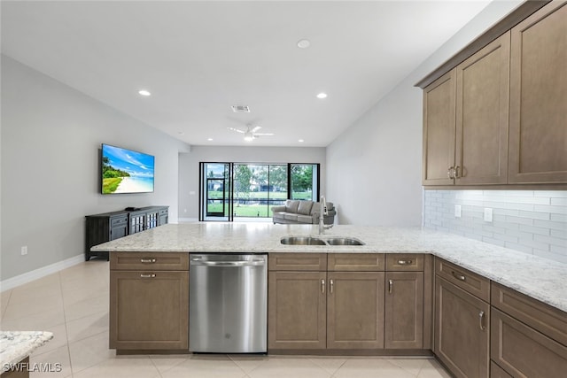 kitchen featuring stainless steel dishwasher, sink, light stone counters, and kitchen peninsula