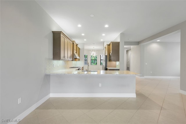 kitchen with light stone countertops, kitchen peninsula, light tile patterned floors, and sink