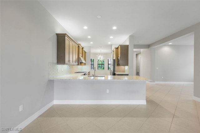 kitchen featuring recessed lighting, under cabinet range hood, a sink, baseboards, and a peninsula
