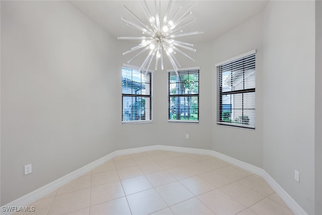 empty room with a chandelier and light tile patterned flooring