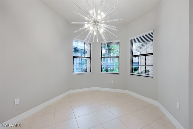 spare room featuring light tile patterned floors, a chandelier, and baseboards