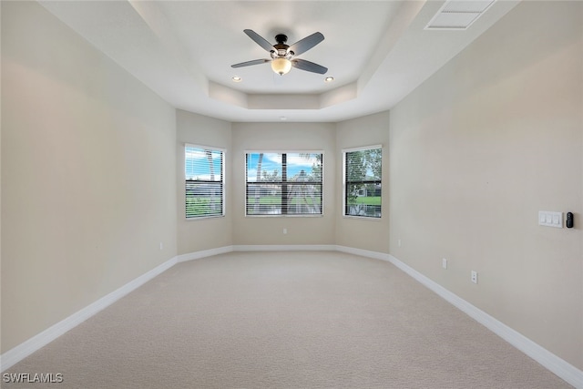 unfurnished room with ceiling fan, light colored carpet, and a raised ceiling