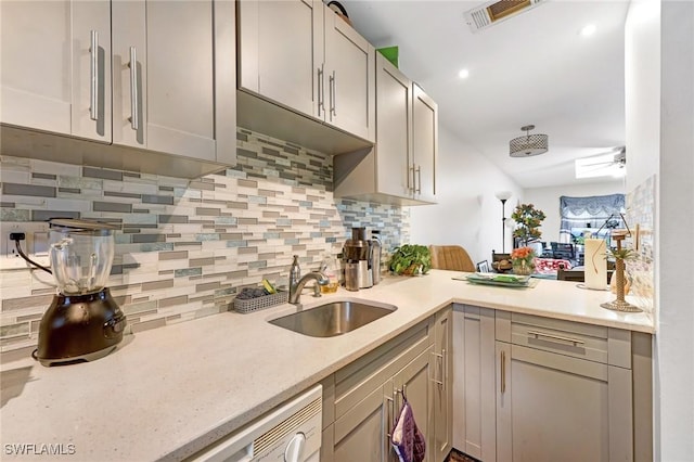 kitchen with backsplash, kitchen peninsula, sink, and white dishwasher