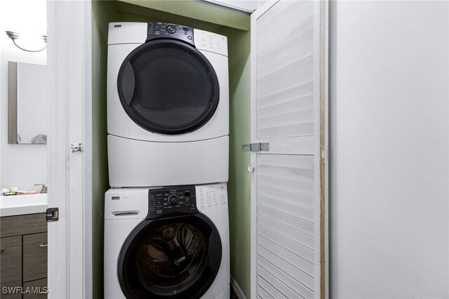 clothes washing area featuring stacked washer and dryer and sink