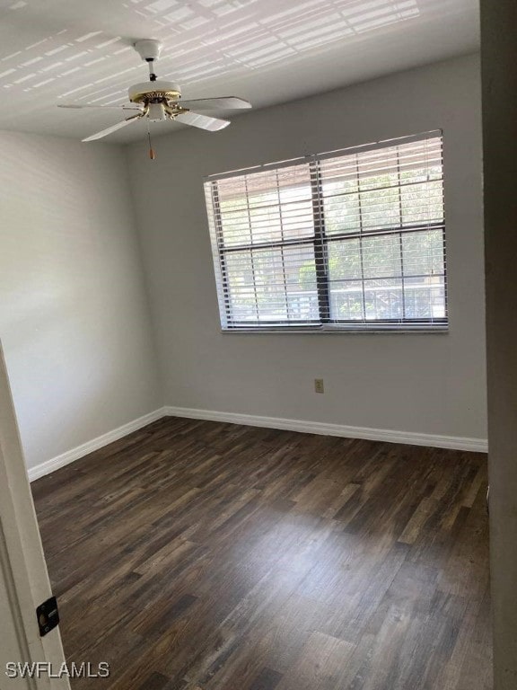 empty room featuring a wealth of natural light, dark wood-type flooring, and ceiling fan