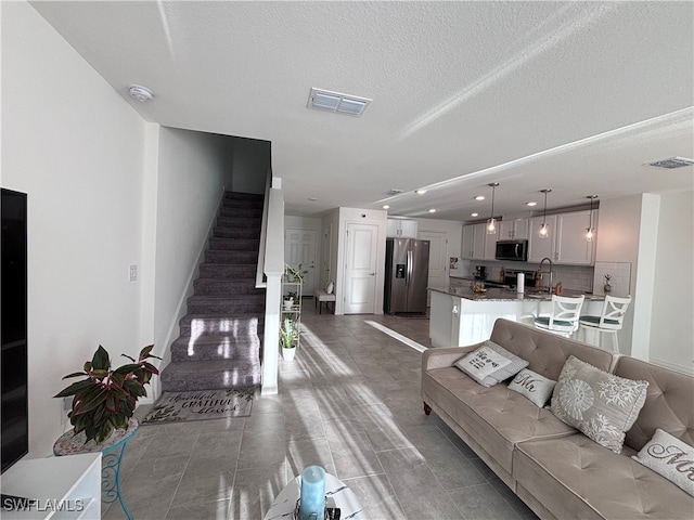 living room with a textured ceiling, sink, and dark tile patterned floors