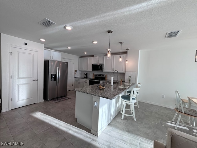 kitchen featuring stainless steel appliances, white cabinets, kitchen peninsula, and hanging light fixtures