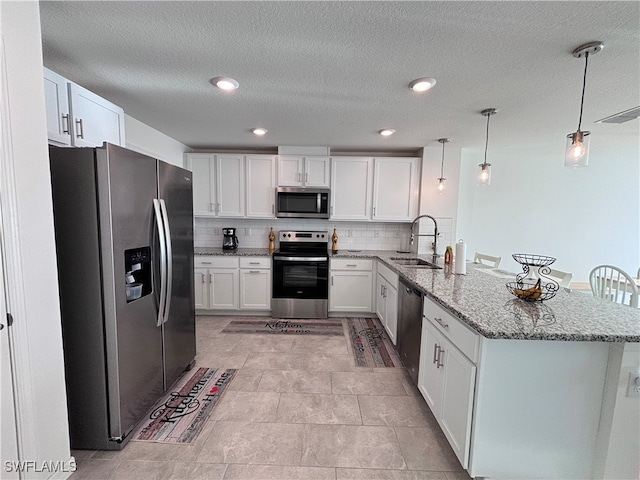 kitchen featuring stainless steel appliances, white cabinetry, kitchen peninsula, and sink