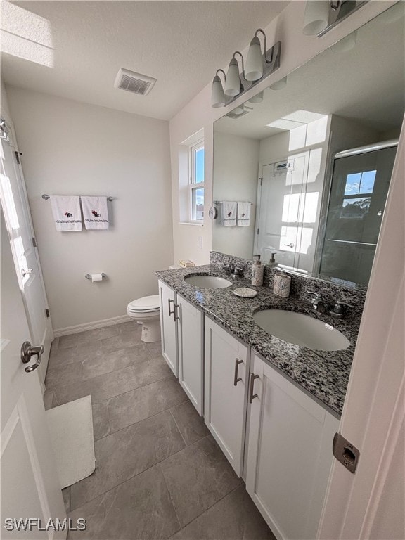 bathroom with a textured ceiling, walk in shower, vanity, and toilet