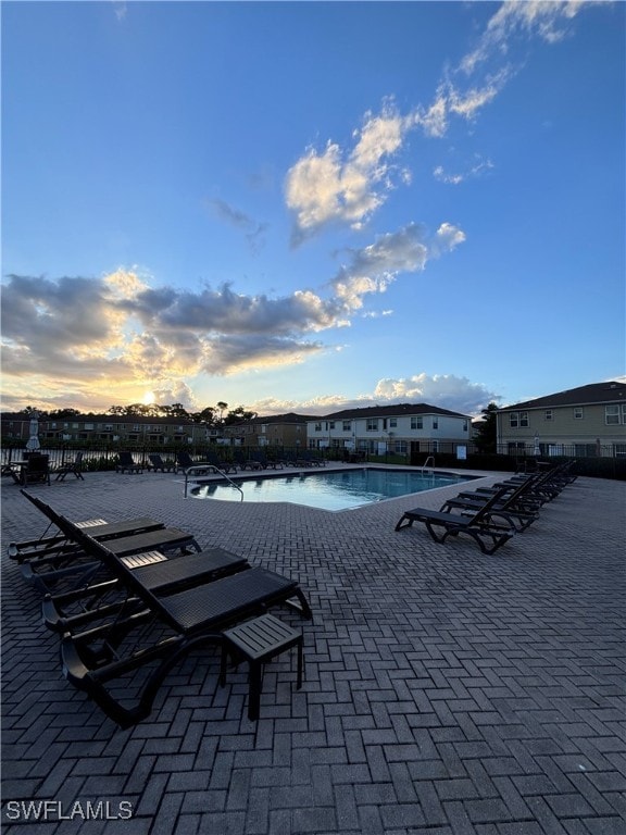 pool at dusk featuring a patio