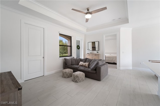 living room featuring ceiling fan, a raised ceiling, ornamental molding, and light hardwood / wood-style flooring