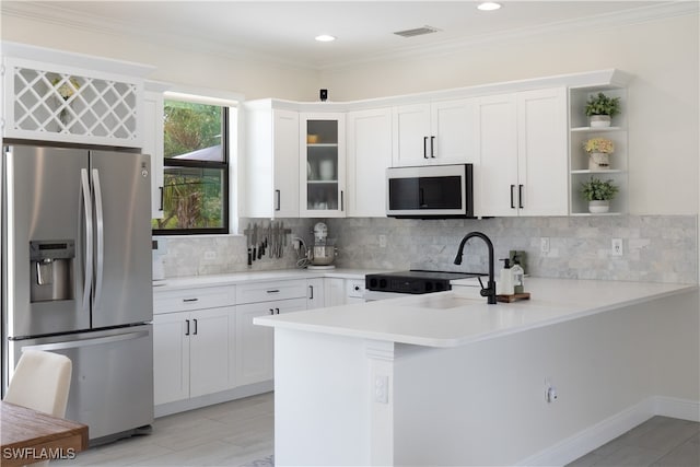 kitchen with kitchen peninsula, tasteful backsplash, stainless steel appliances, and white cabinets