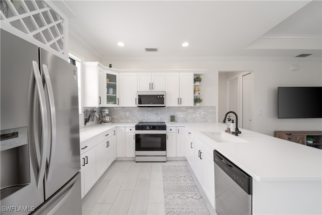 kitchen featuring appliances with stainless steel finishes, tasteful backsplash, white cabinets, kitchen peninsula, and sink