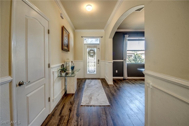 entryway featuring arched walkways, a wainscoted wall, dark wood-style flooring, visible vents, and crown molding