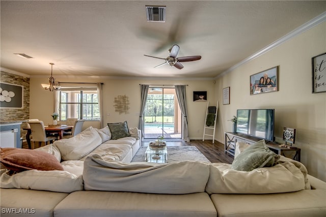 living room with ceiling fan with notable chandelier, wood-type flooring, and ornamental molding