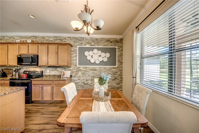 kitchen featuring a chandelier, light stone counters, wood finished floors, appliances with stainless steel finishes, and crown molding