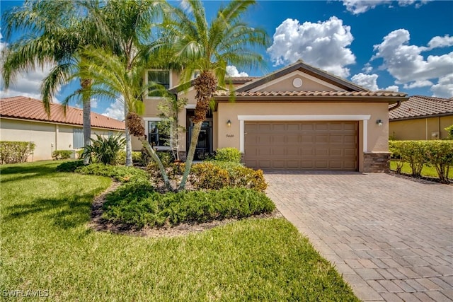 mediterranean / spanish house with a garage, decorative driveway, a front lawn, and stucco siding