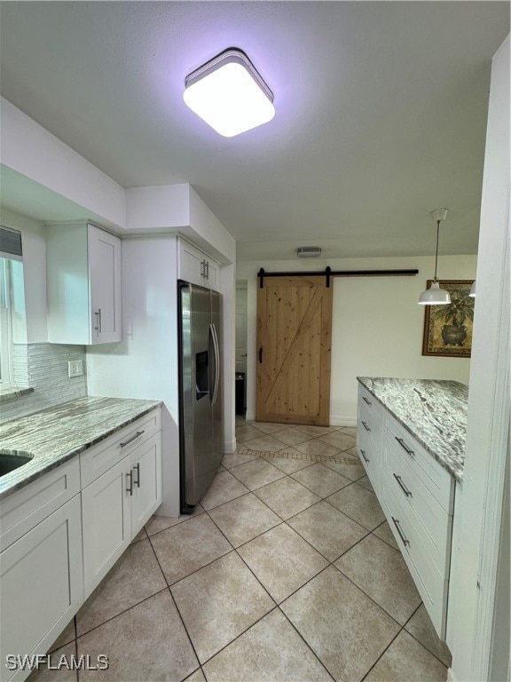 kitchen featuring white cabinets, a barn door, pendant lighting, and stainless steel fridge with ice dispenser