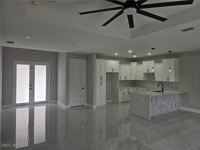 kitchen with white cabinetry, sink, french doors, ceiling fan, and a tray ceiling