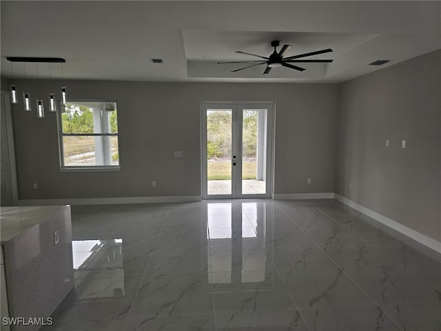 spare room with ceiling fan, french doors, and a tray ceiling