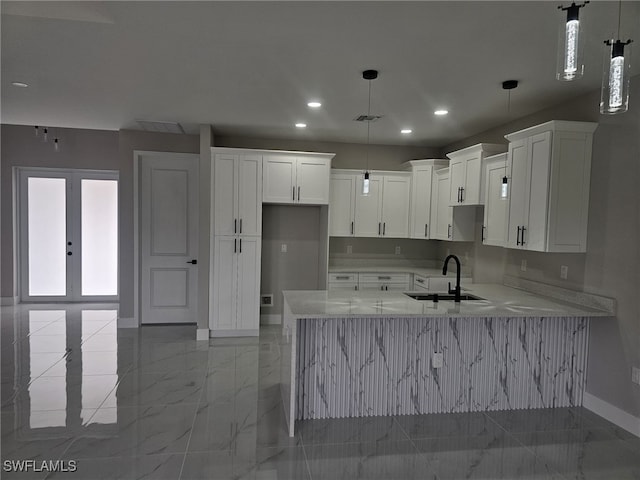 kitchen with decorative light fixtures, sink, white cabinets, and light stone countertops