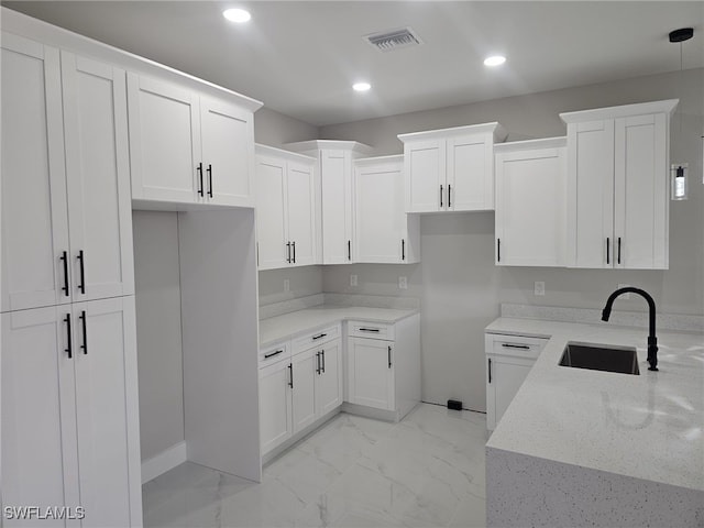 kitchen featuring light stone countertops, sink, pendant lighting, and white cabinets