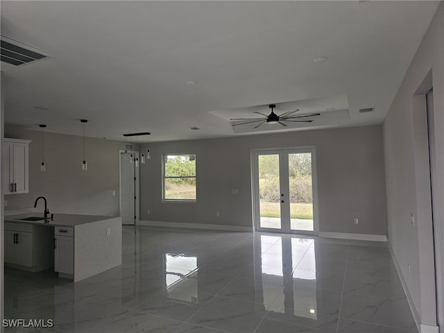 interior space with sink, ceiling fan, french doors, and a tray ceiling