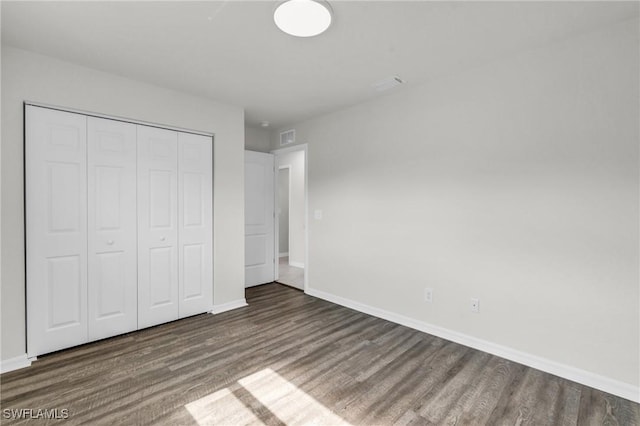 unfurnished bedroom featuring dark hardwood / wood-style floors and a closet