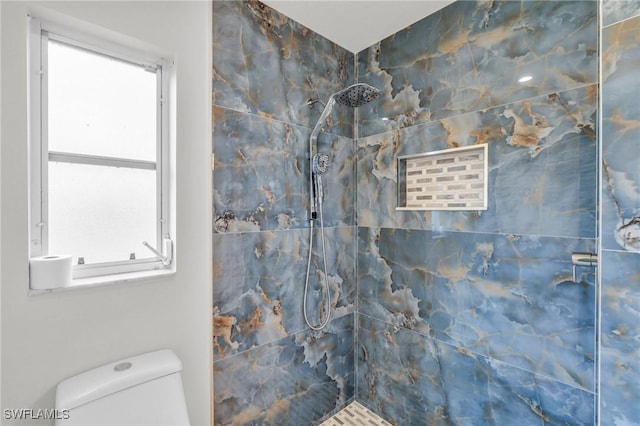 bathroom with a tile shower and toilet