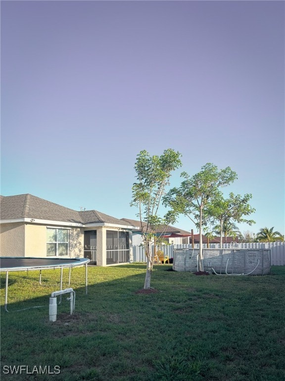 view of yard featuring a trampoline and a sunroom