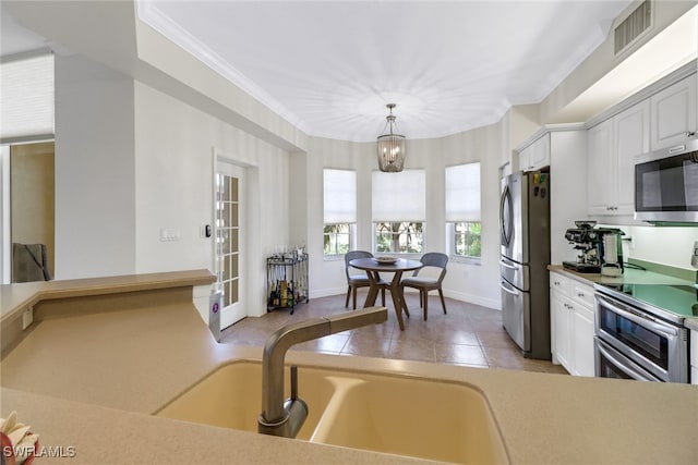 kitchen featuring white cabinets, a notable chandelier, stainless steel appliances, and decorative light fixtures