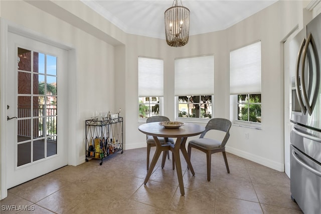 dining room with ornamental molding, light tile patterned floors, and a notable chandelier