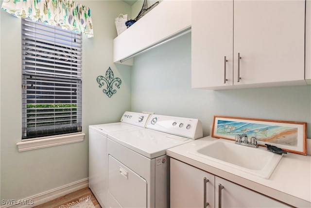 clothes washing area with cabinets, light hardwood / wood-style flooring, sink, and washing machine and dryer