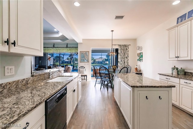 kitchen with hanging light fixtures, a kitchen island, light hardwood / wood-style flooring, dishwasher, and light stone countertops