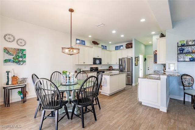 dining room featuring an inviting chandelier, light hardwood / wood-style flooring, and sink