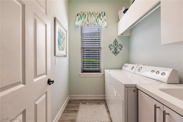 clothes washing area featuring cabinets, light hardwood / wood-style flooring, independent washer and dryer, and a healthy amount of sunlight