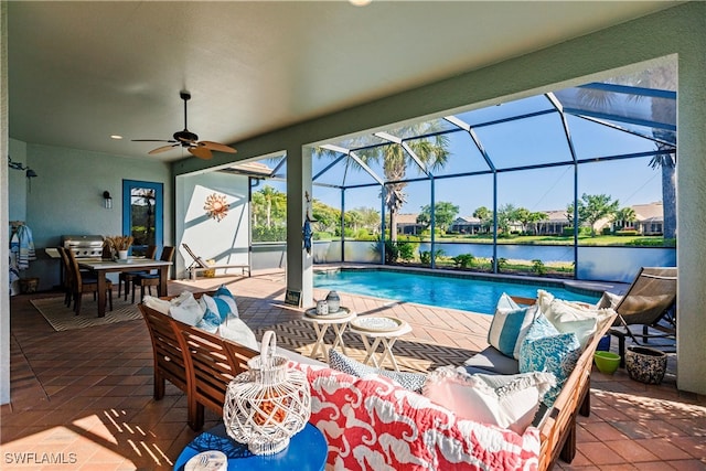 view of swimming pool with ceiling fan, a lanai, a water view, and a patio area