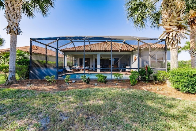 back of house featuring a lawn, glass enclosure, and a patio area