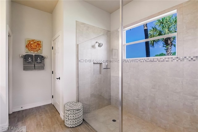 bathroom with a tile shower and wood-type flooring