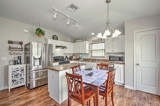 kitchen featuring stainless steel appliances, pendant lighting, white cabinets, a center island, and lofted ceiling